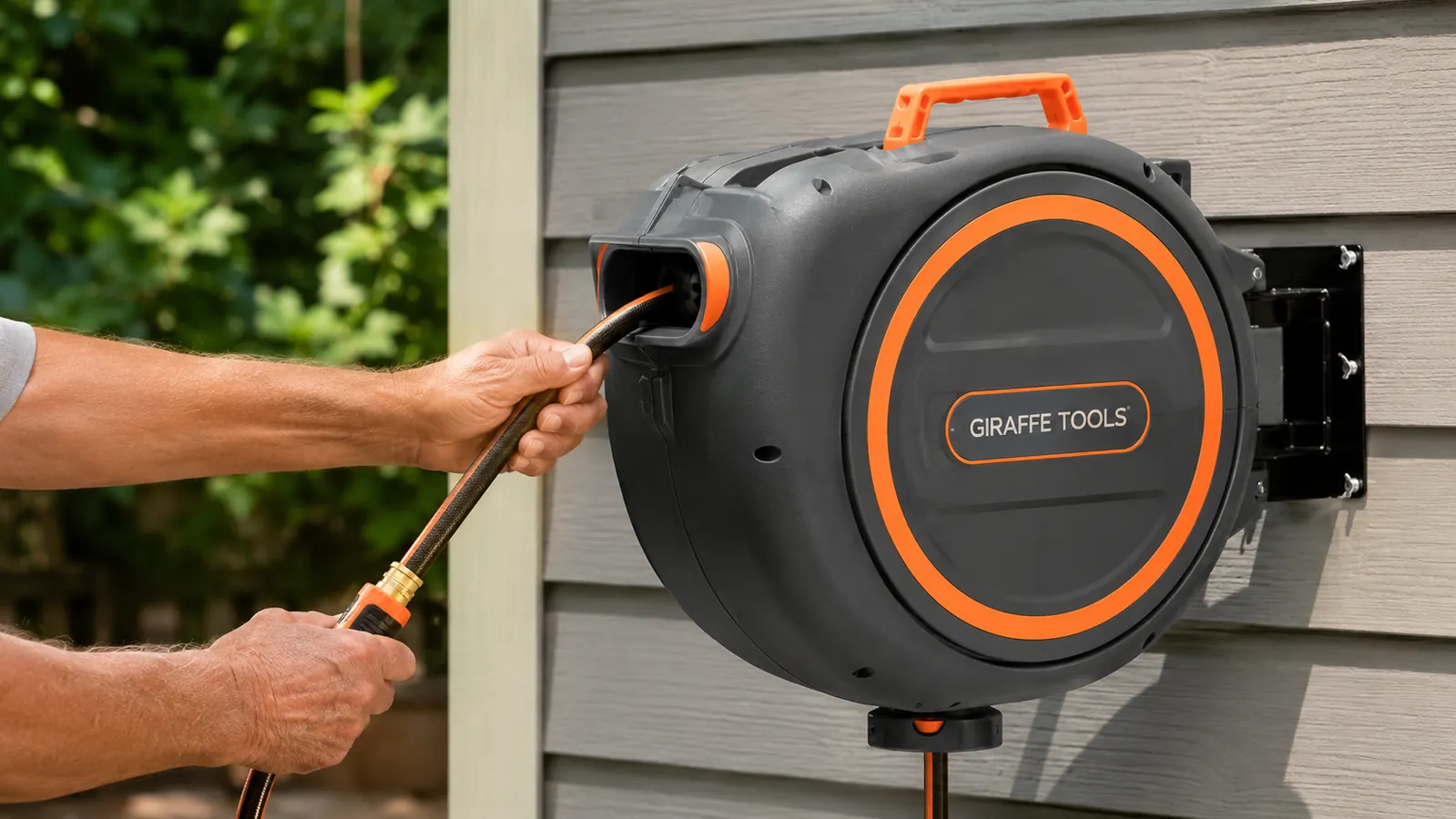 Close-up of a hand pulling hose from a wall-mounted retractable garden hose reel outside a garage